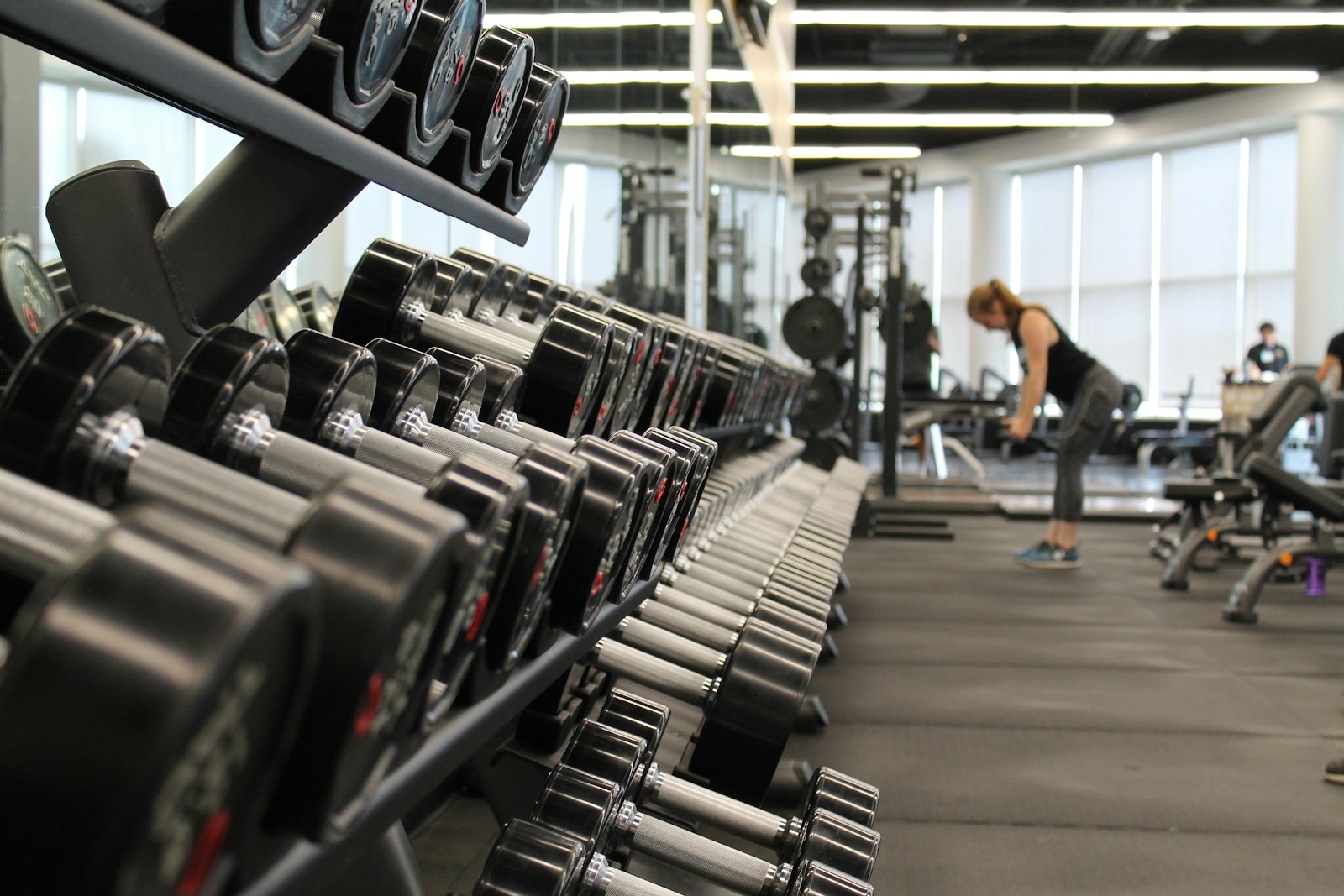 A bright gym with dumbbells and people training